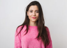 Uśmiechnięta brunetka w różowym swetrze